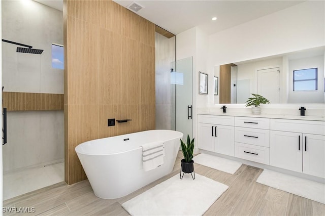 bathroom with hardwood / wood-style flooring, vanity, independent shower and bath, and tile walls