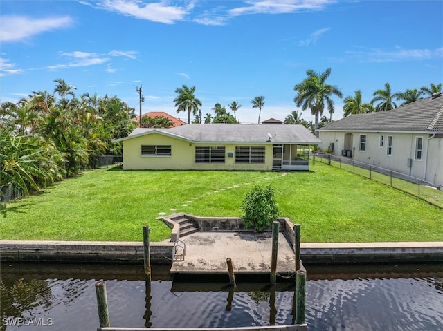 rear view of property featuring a lawn and a water view