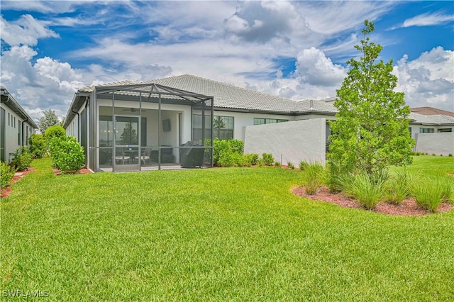 rear view of house featuring a lanai and a lawn