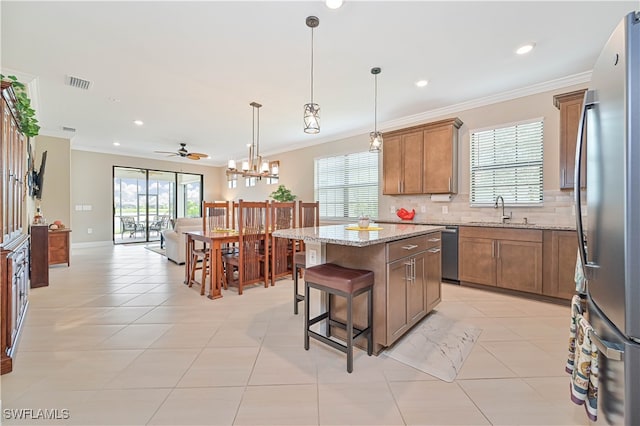 kitchen featuring tasteful backsplash, stainless steel appliances, light stone counters, ceiling fan, and a kitchen island