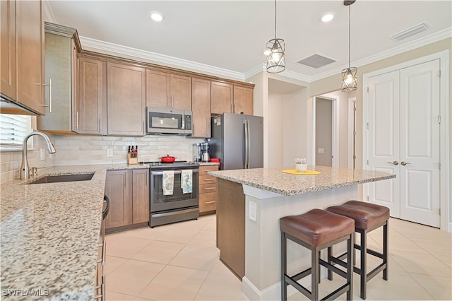 kitchen featuring light tile patterned floors, appliances with stainless steel finishes, a center island, and sink