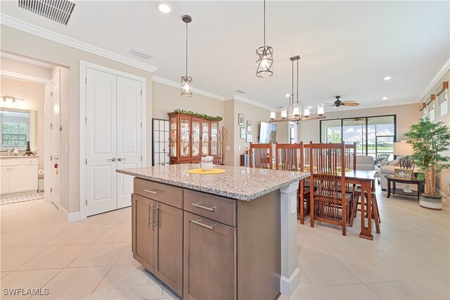 kitchen featuring ceiling fan with notable chandelier, light tile patterned floors, light stone countertops, ornamental molding, and decorative light fixtures