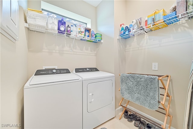 clothes washing area featuring light tile patterned flooring and washer and dryer