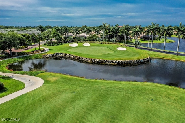 view of property's community with view of golf course, a yard, and a water view