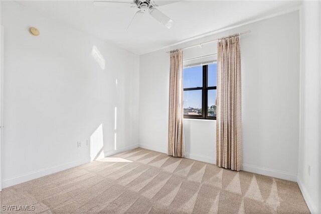 carpeted spare room featuring a ceiling fan and baseboards