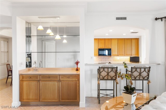 kitchen with black microwave, ornamental molding, visible vents, and decorative backsplash