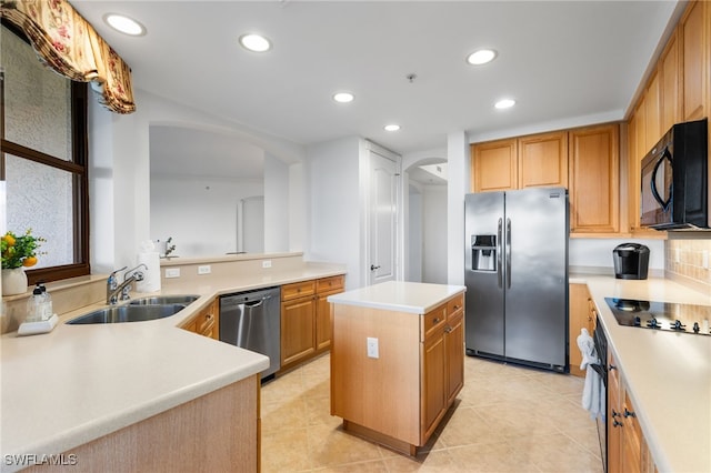 kitchen featuring arched walkways, black appliances, a kitchen island, and a sink