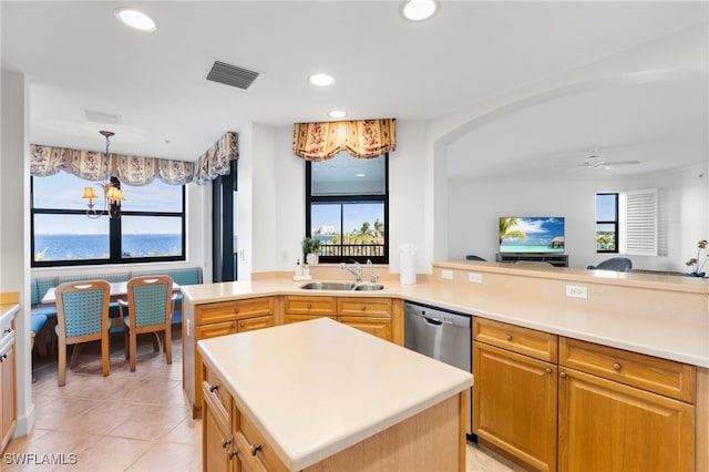 kitchen with sink, a water view, a center island, stainless steel dishwasher, and ceiling fan with notable chandelier