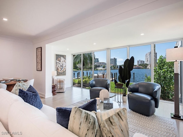 living room with a water view, floor to ceiling windows, and light hardwood / wood-style flooring