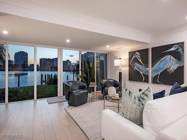 living room featuring wood-type flooring, floor to ceiling windows, and a water view