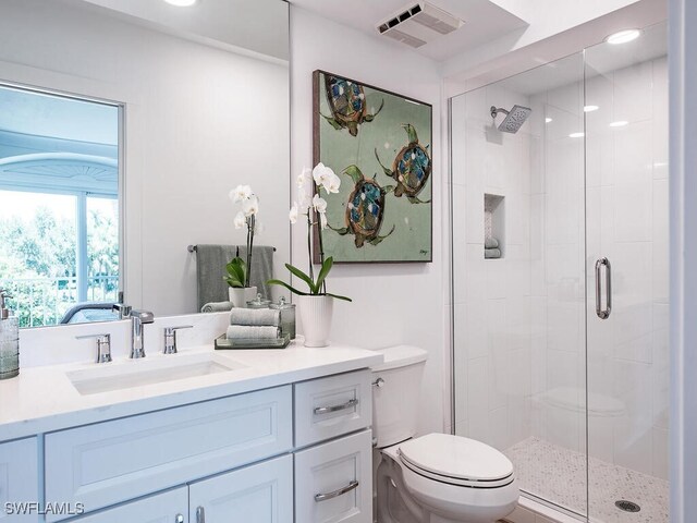 bathroom featuring vanity, toilet, and a shower with shower door