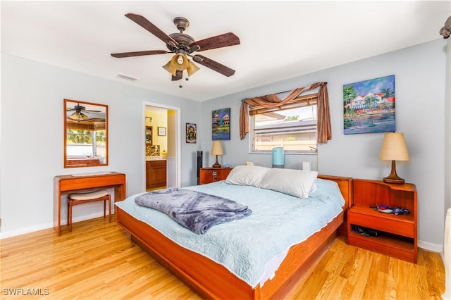 bedroom with ceiling fan, ensuite bathroom, multiple windows, and light wood-type flooring