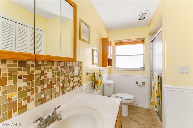 bathroom featuring walk in shower, toilet, vanity, tile patterned flooring, and backsplash