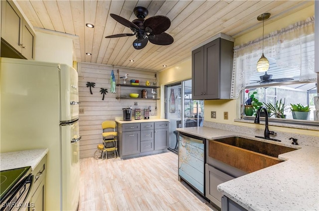 kitchen featuring sink, hanging light fixtures, electric range, dishwashing machine, and light stone countertops