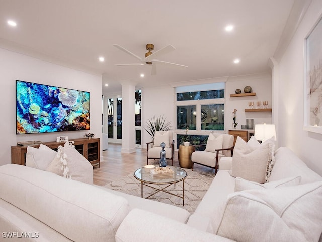 living room featuring ornamental molding, ceiling fan, and light wood-type flooring