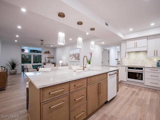 kitchen featuring sink, white cabinetry, decorative light fixtures, light wood-type flooring, and white appliances