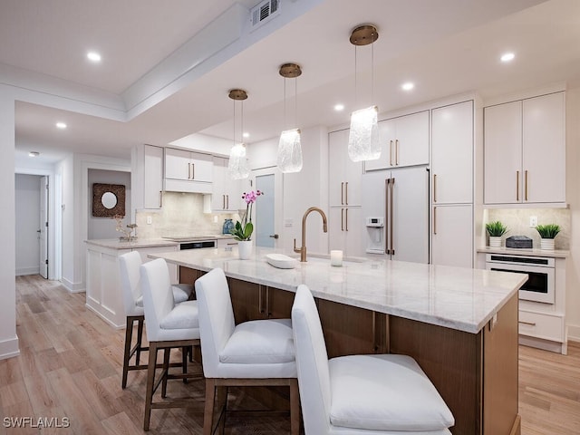 kitchen featuring white cabinetry, a kitchen island, high quality fridge, and oven