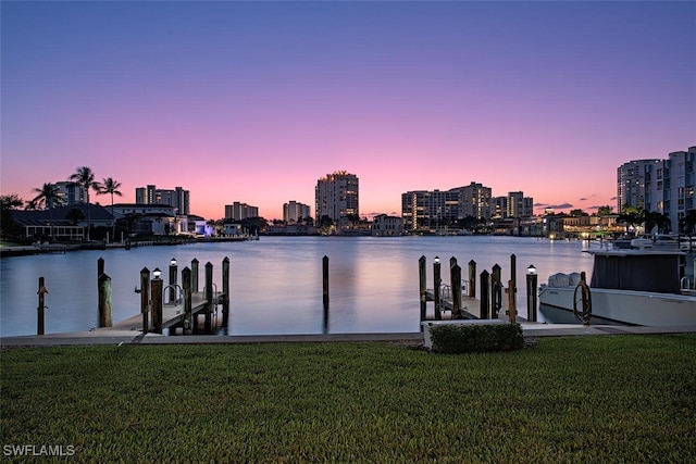 view of dock with a lawn and a water view