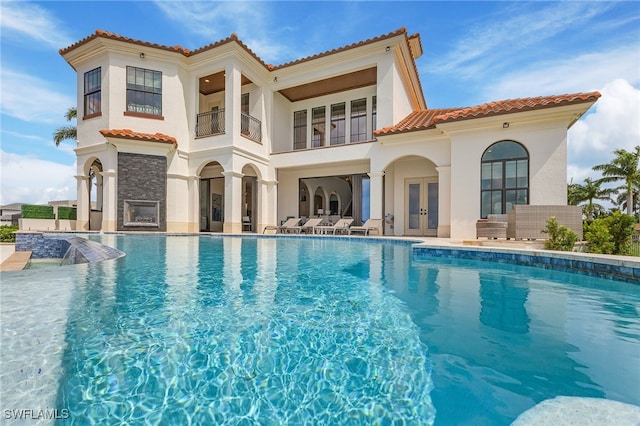 rear view of house featuring french doors, a balcony, and a patio