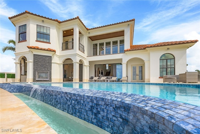 back of house featuring pool water feature, a patio, a balcony, and french doors