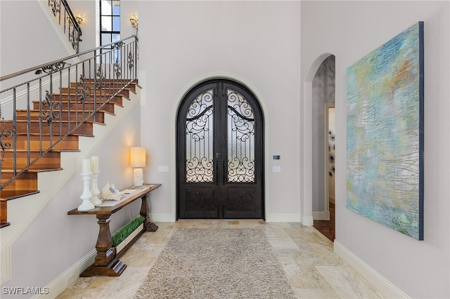 614 Coral Dr, Cape Coral, FL 33904 - entryway with arched walkways, a towering ceiling, french doors, and baseboards