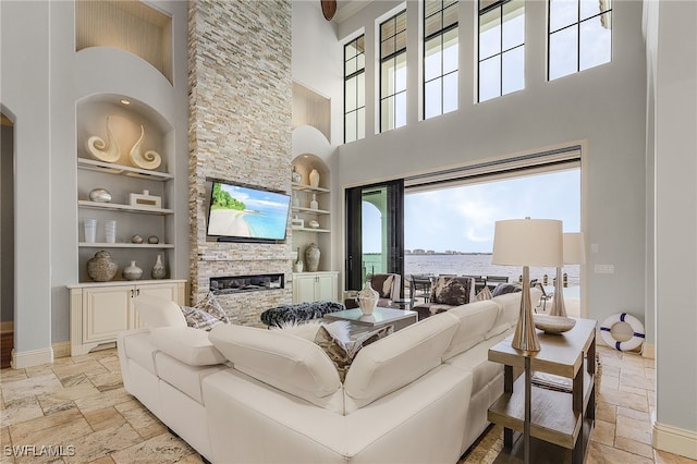 living room featuring a fireplace, built in features, and a high ceiling