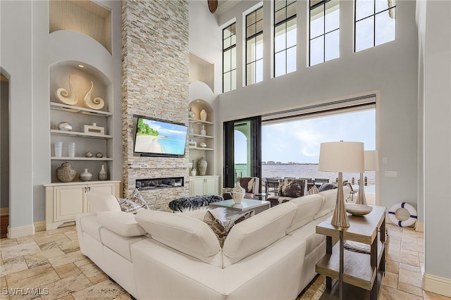 614 Coral Dr, Cape Coral, FL 33904 - living area with built in features, baseboards, a high ceiling, a fireplace, and stone tile floors
