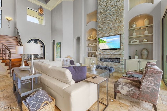 living room with crown molding, a high ceiling, a fireplace, and built in features