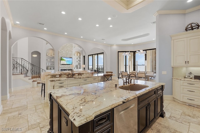 kitchen with light stone counters, stainless steel dishwasher, a spacious island, and sink