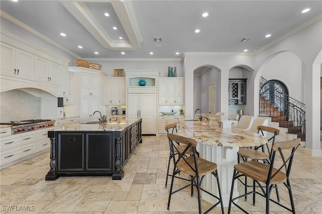 kitchen with a kitchen breakfast bar, decorative backsplash, a large island, and light stone counters