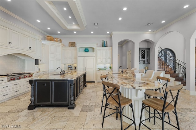 614 Coral Dr, Cape Coral, FL 33904 - kitchen featuring a large island with sink, dark cabinets, stainless steel gas stovetop, a breakfast bar, and stone tile flooring
