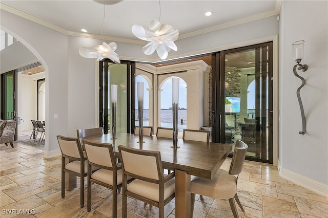 dining room with an inviting chandelier, ornamental molding, and a water view