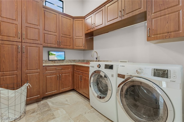 clothes washing area featuring cabinets, sink, and washer and dryer