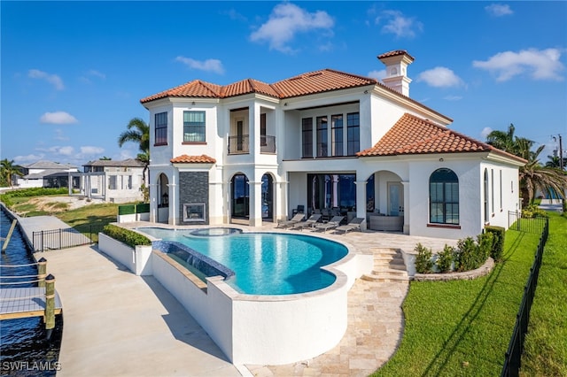 rear view of house featuring a lawn, a balcony, a swimming pool with hot tub, and a patio area