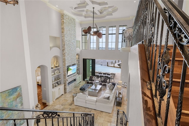 living room featuring ornamental molding, a towering ceiling, and a fireplace