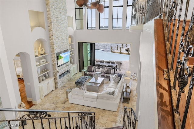 614 Coral Dr, Cape Coral, FL 33904 - living room with built in features, arched walkways, stone tile floors, a stone fireplace, and a high ceiling
