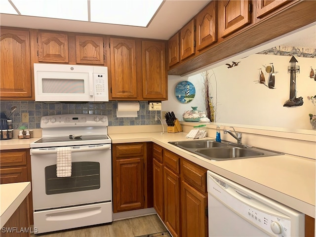 kitchen with sink, tasteful backsplash, light hardwood / wood-style floors, and white appliances