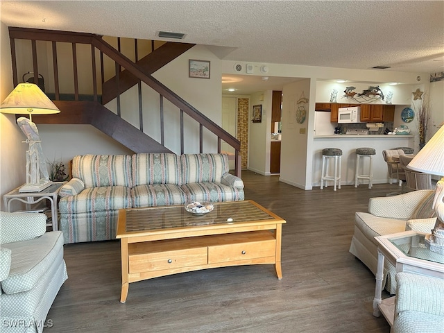 living room with a textured ceiling and dark hardwood / wood-style floors