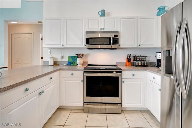 kitchen with appliances with stainless steel finishes, light tile patterned flooring, and white cabinets