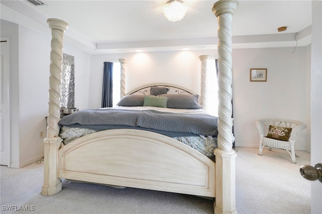 bedroom with ornate columns and light colored carpet