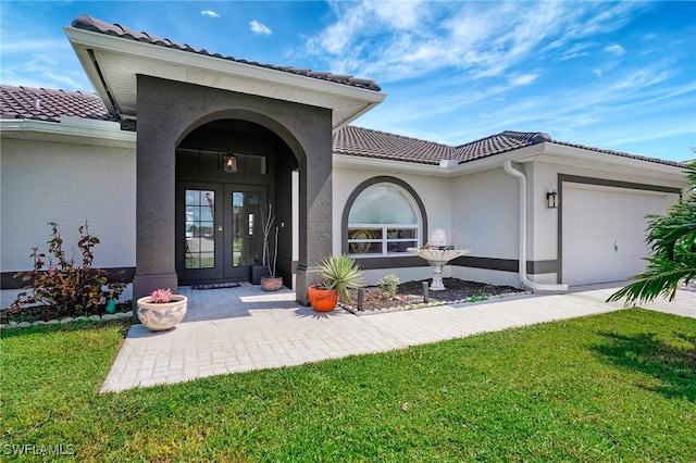 doorway to property with french doors, a yard, and a garage