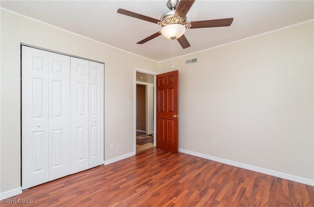 unfurnished bedroom featuring crown molding, dark wood-type flooring, a closet, and ceiling fan