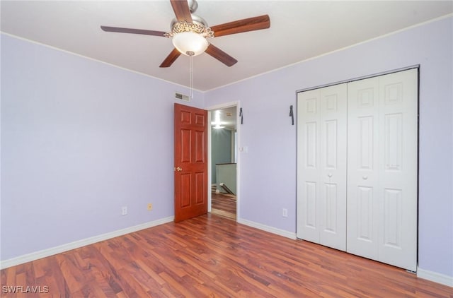 unfurnished bedroom with hardwood / wood-style flooring, ceiling fan, and a closet