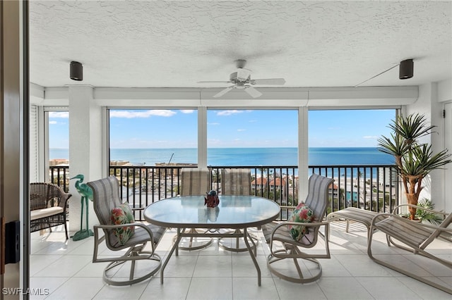 sunroom / solarium featuring ceiling fan, a water view, and a healthy amount of sunlight