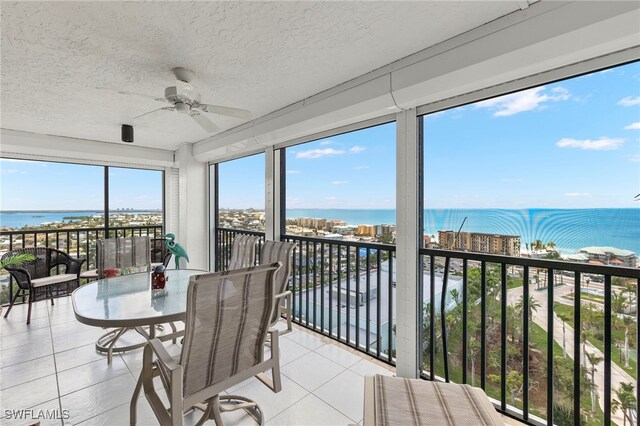 sunroom featuring ceiling fan and a water view