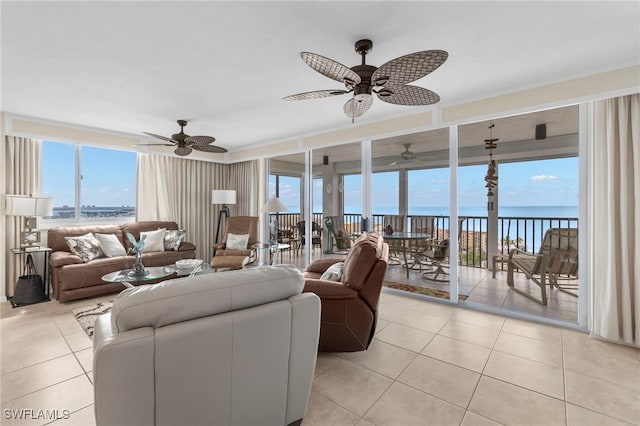 living room featuring ceiling fan, a water view, and light tile patterned floors