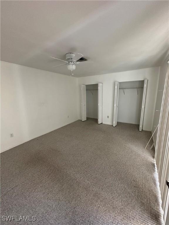 unfurnished bedroom with ceiling fan, carpet, and two closets