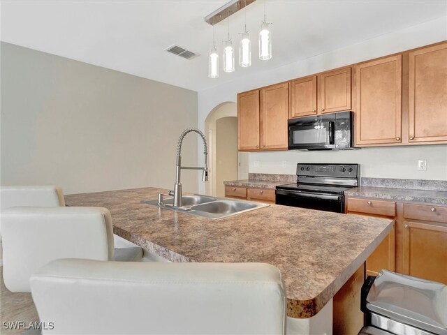 kitchen featuring black appliances, a kitchen island with sink, a breakfast bar, and sink