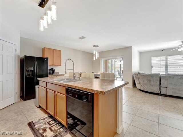 kitchen with black appliances, a kitchen island with sink, sink, pendant lighting, and light tile patterned flooring