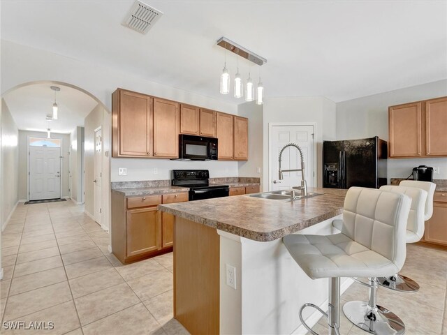 kitchen featuring sink, decorative light fixtures, a kitchen bar, a kitchen island with sink, and black appliances